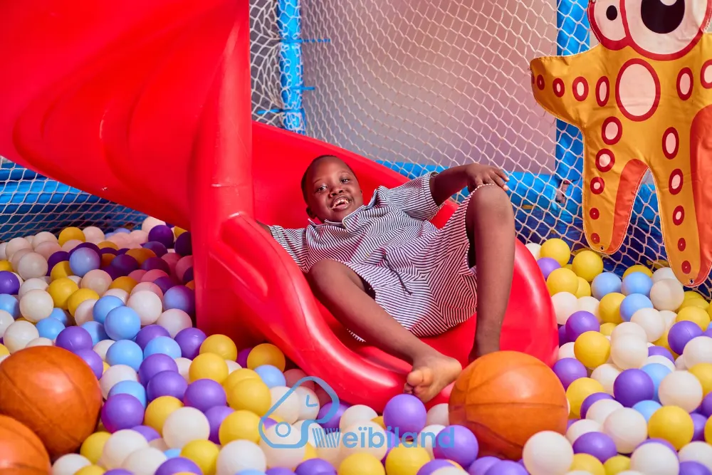 Enfant qui glisse dans la piscine à balles
